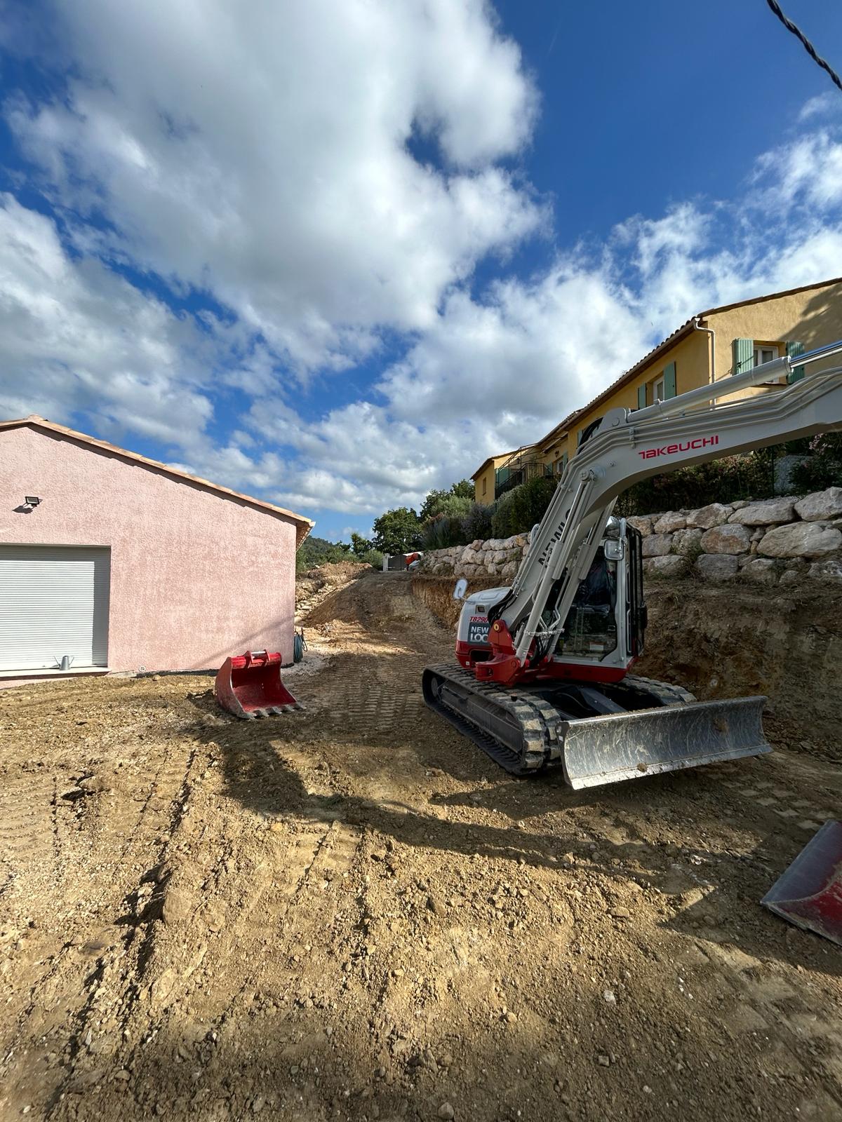 Mini-pelle Takeuchi devant propriété